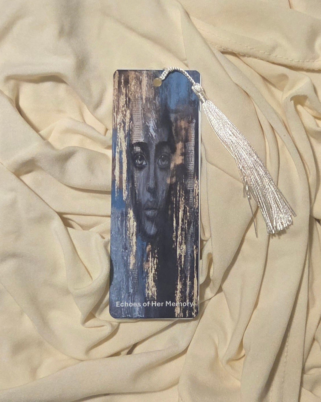 Aluminum Bookmark with a portrait and a blue background with golden accents printed on it. Includes a white tassel.