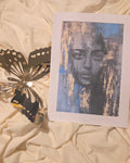 Artistic print of a face on a white card with golden accents