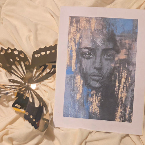 Artistic print of a face on a white card with golden accents