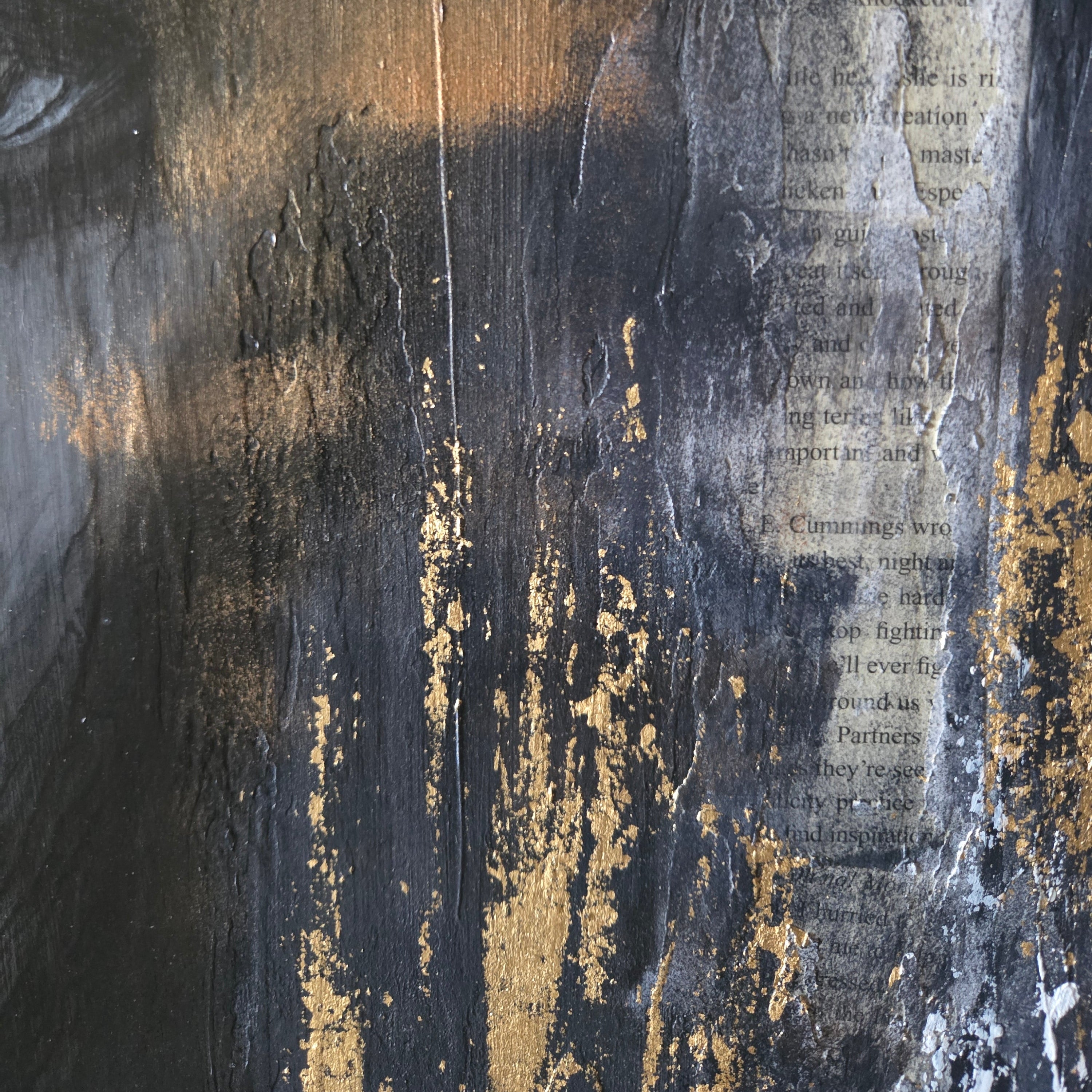 Close-up of a textured surface with gold accents and parts of a book's page.